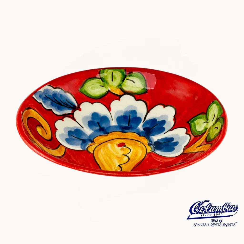 Colorful ceramic plate with floral design on a red background, featuring the Columba brand logo.