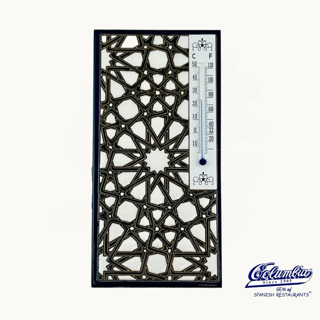 Decorative metal panel with geometric pattern and thermometer on a white background