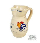 A ceramic serving pitcher with a rooster design, predominantly beige in color with blue and red accents.