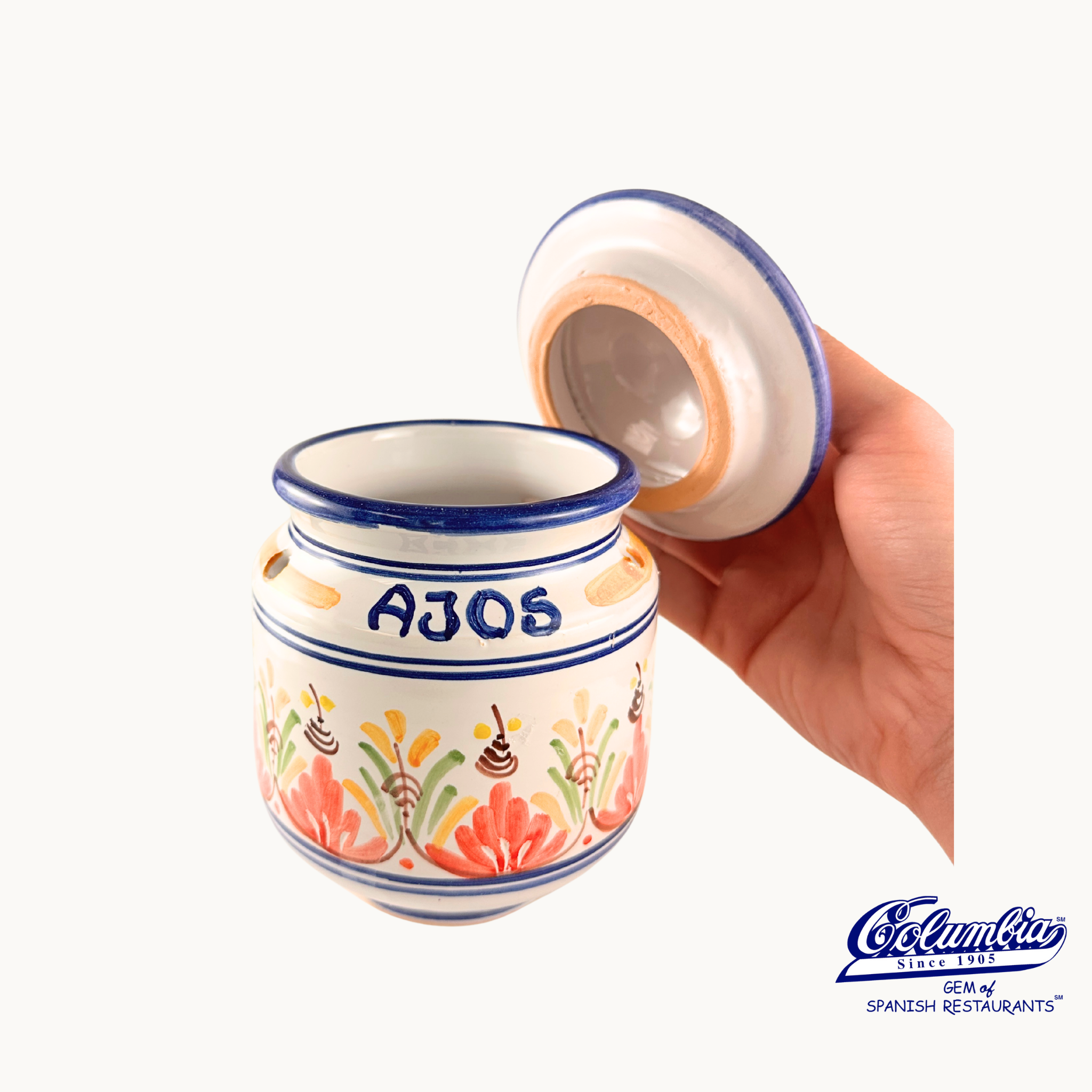 Ceramic jar with 'AJOS' text held by a hand on a white background, featuring Colmenar logo.