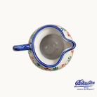 Ceramic creamer with floral design and blue rim on a white background, featuring the Columbus brand logo.