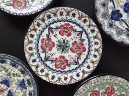 A collection of ceramic coasters with floral and geometric patterns in various colors.
